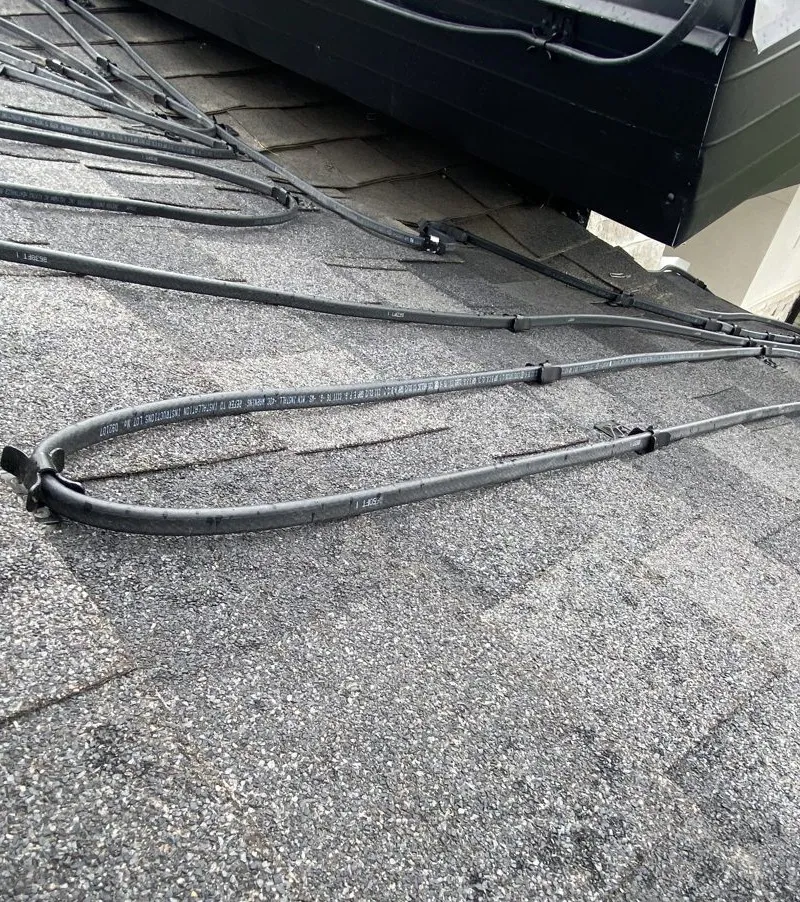 Self-regulating heat cable routed in loops along a roof edge, held down by glued clips