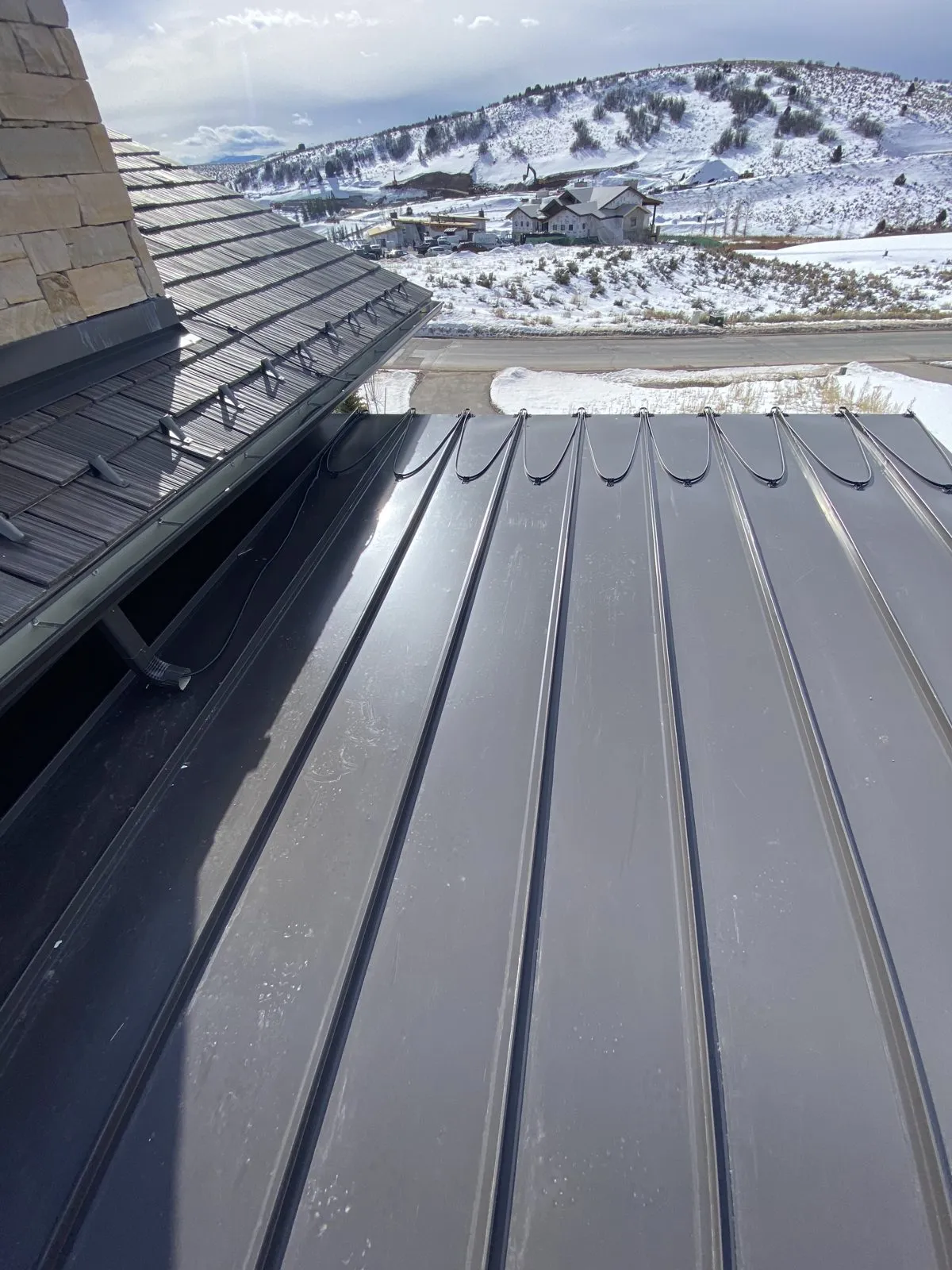 Standing-seam metal roof under winter snow in Anchorage