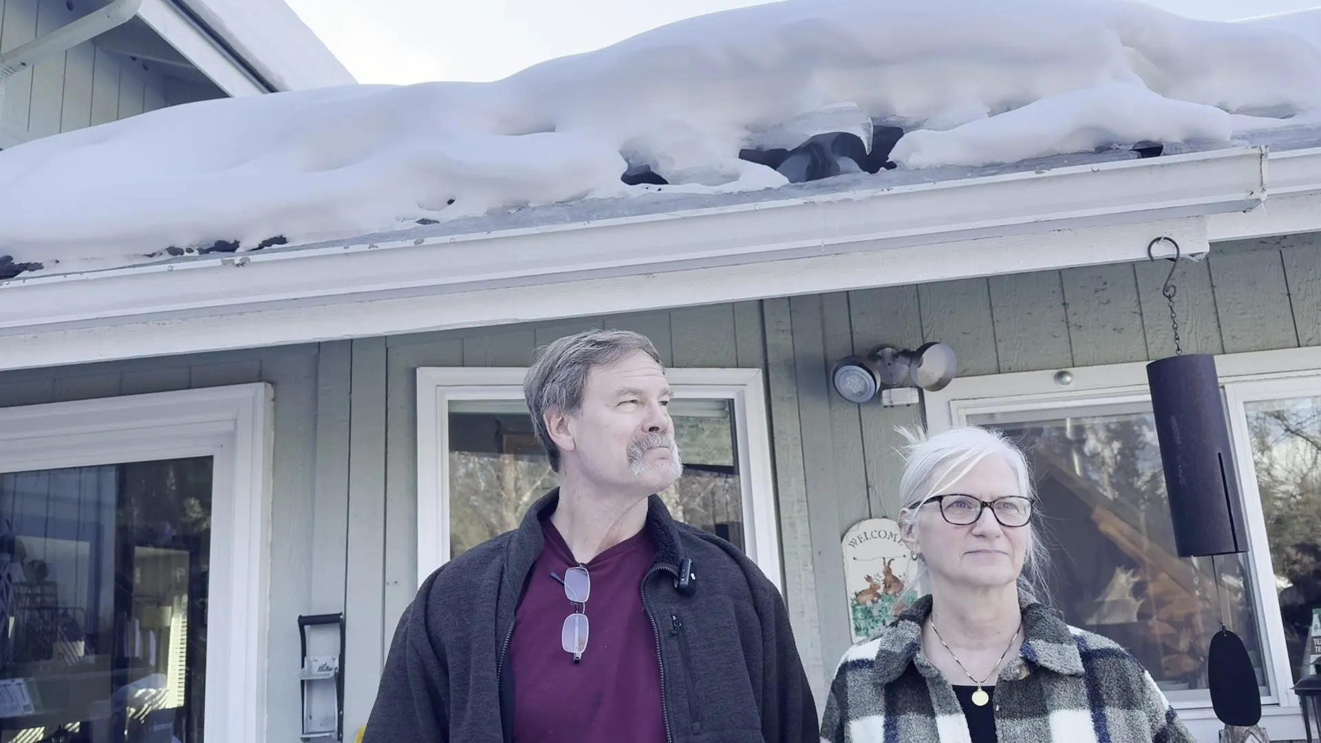 Anchorage homeowners under their snow-loaded eave